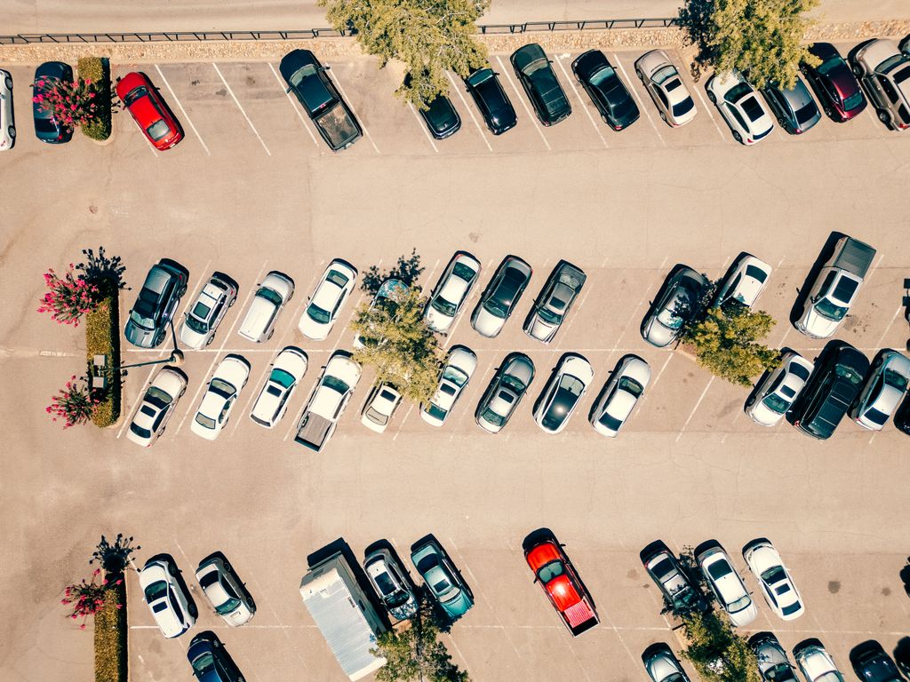Aerial shot of a parking lot filled with cars on a bright, sunny day.