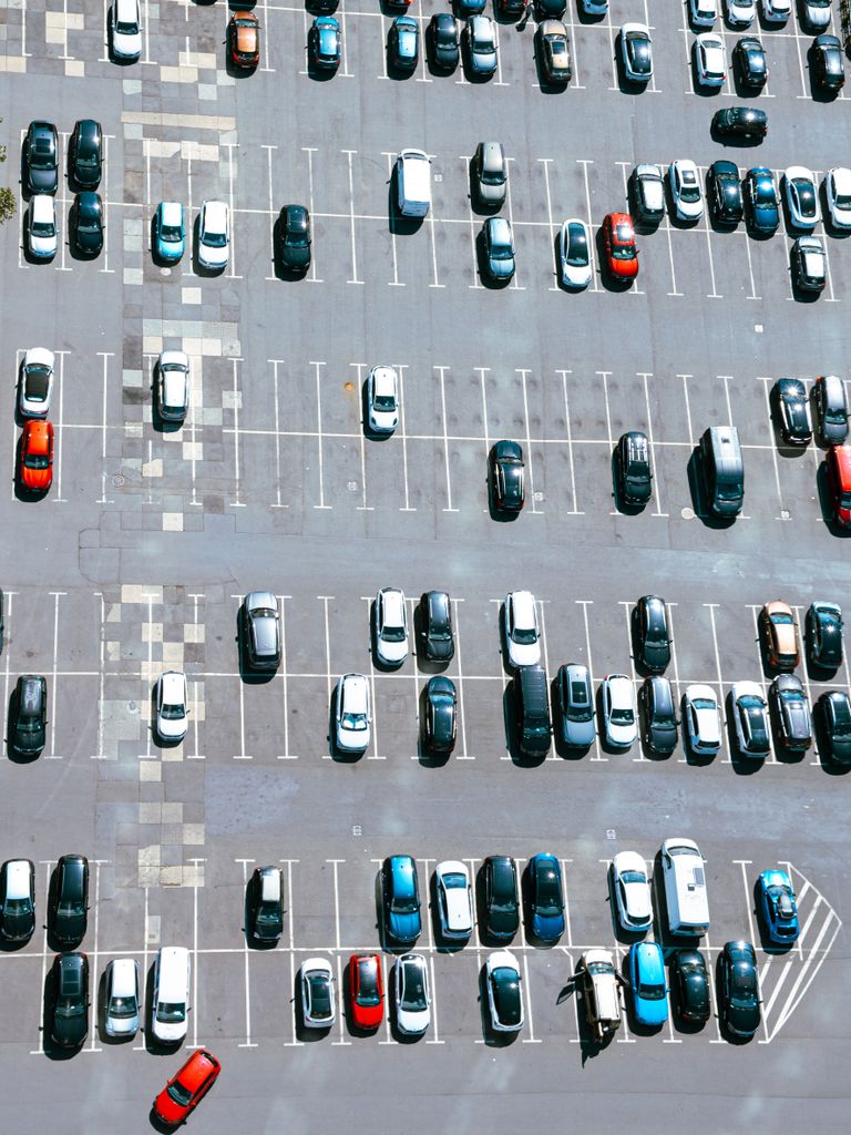 High-angle view of a busy urban parking lot with various cars parked under bright daylight.